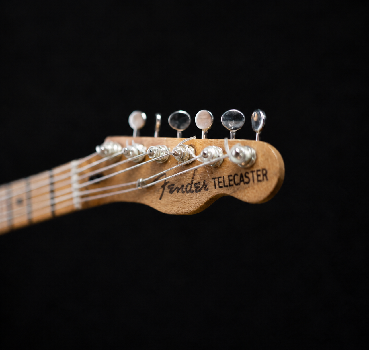 Macro shot of the miniature Fender Telecaster headstock with hand-wound tuners and logo