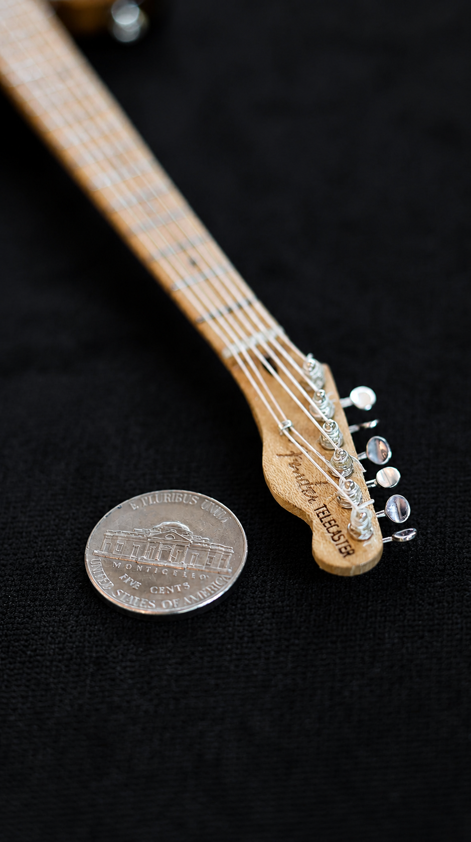 Miniature Telecaster headstock and neck beside a Jefferson nickel showing true scale