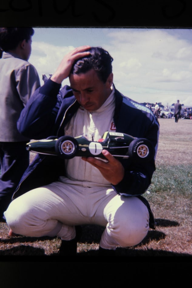 A driver crouching trackside with the hand-built Lotus model