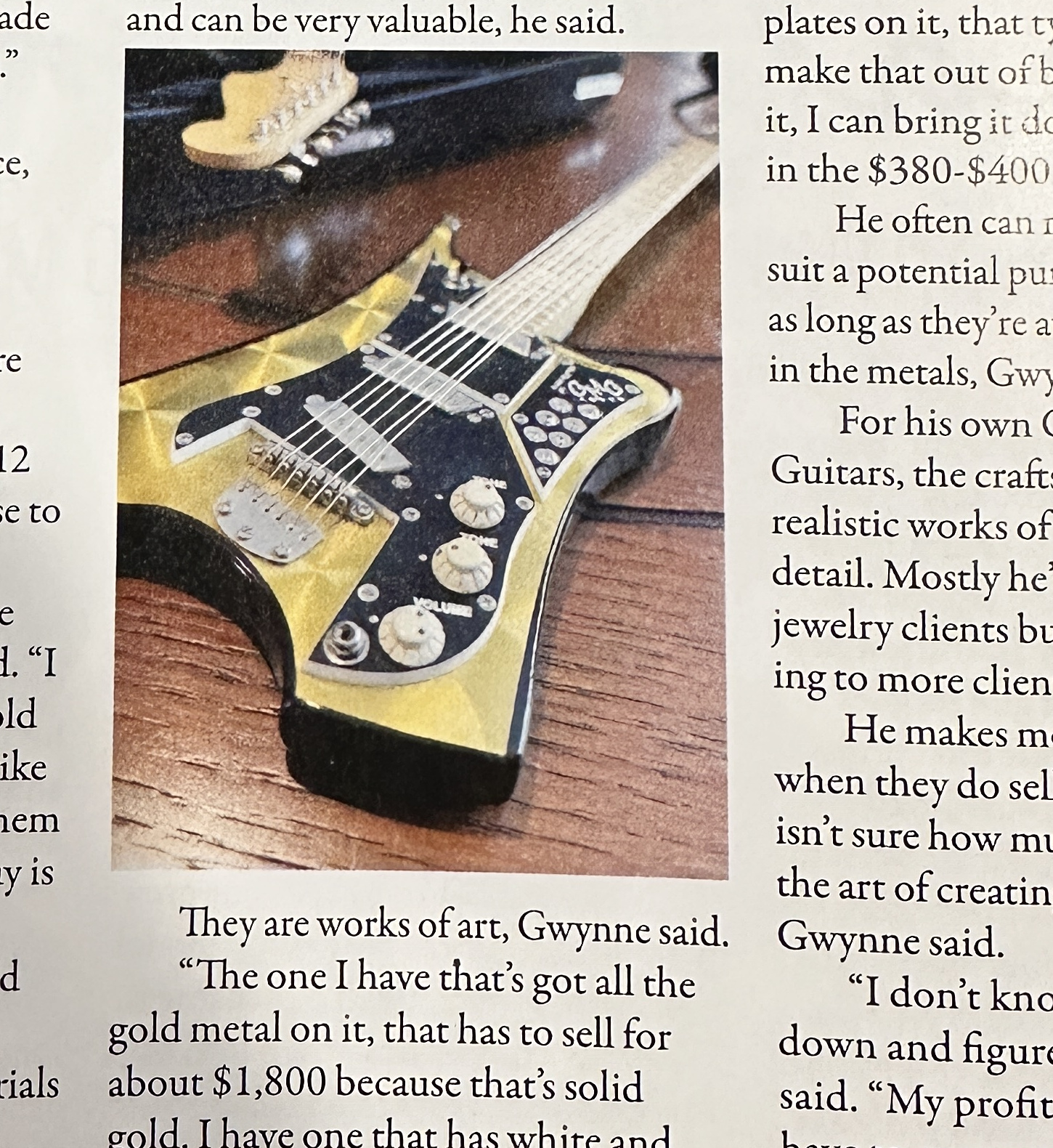 Close-up of a finished gold-toned miniature guitar showing its bridge, strings, controls, and detailed headstock