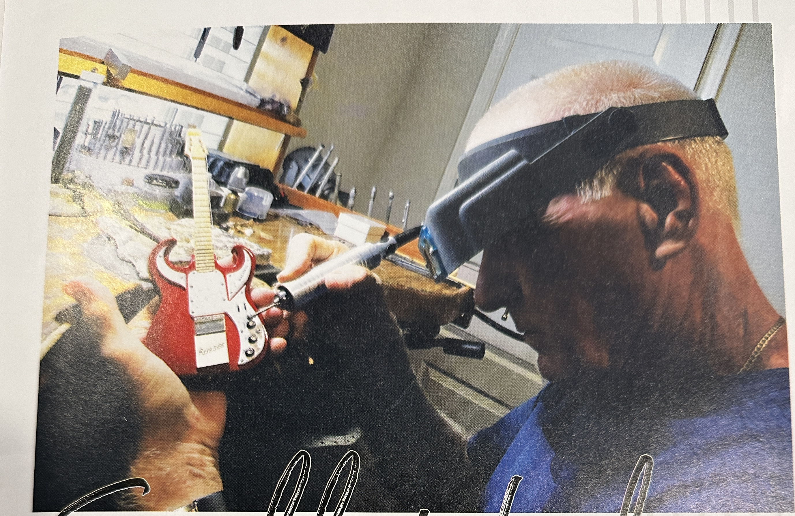 Rob Gwynn working under magnification while shaping a red miniature guitar at his bench